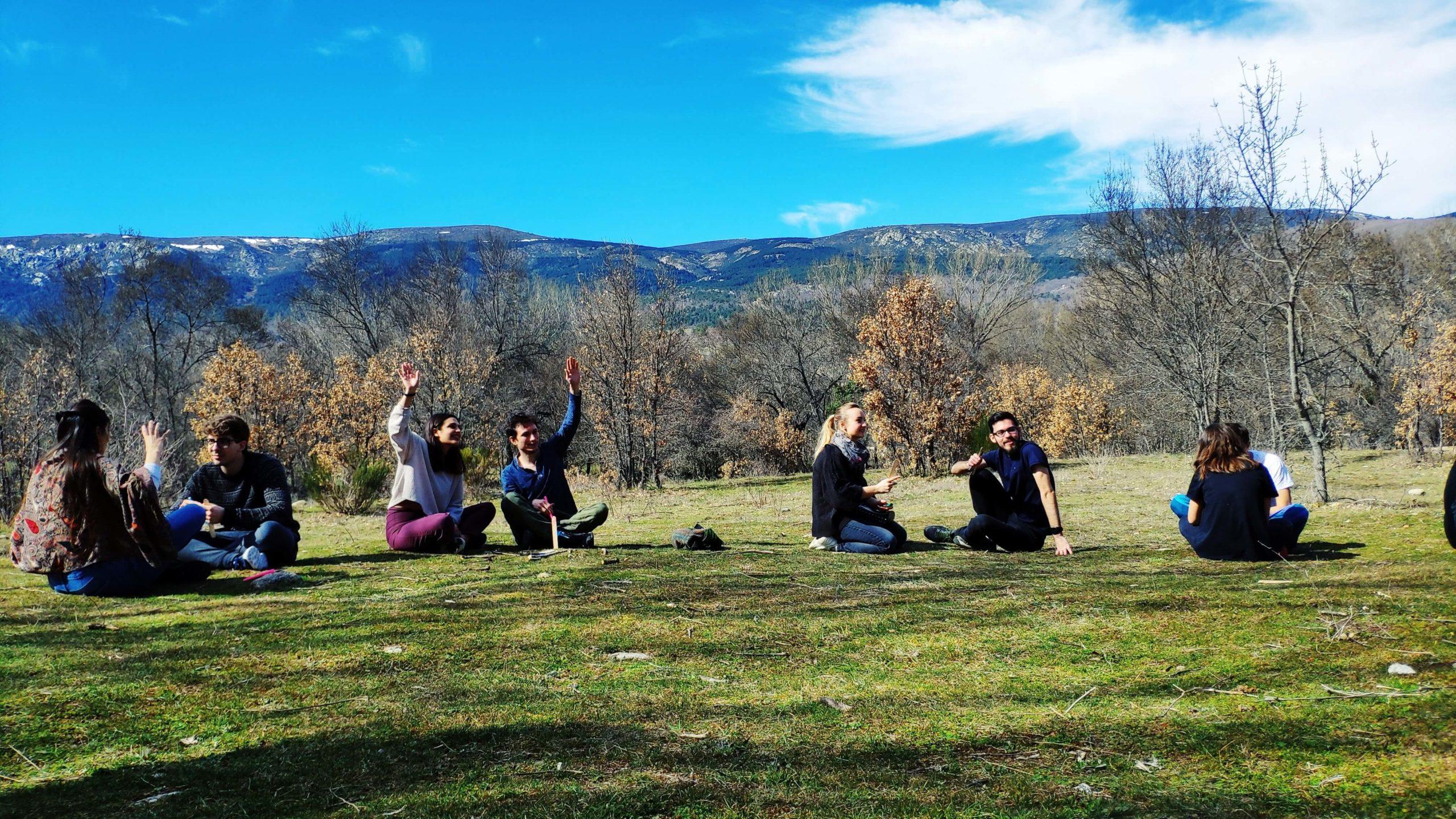 Group sitting in grassy field with mountains in background